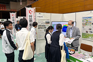 ブースの様子高校生からの環境にやさしいミラクルソル工法に関する質問に回答する金丸部長、辻川主任
